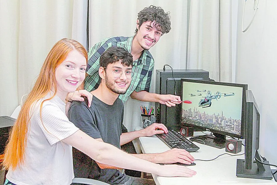 Regiane, Messias e Ramon mostram na tela do computador projeção do carro voador desenvolvido pela Embraer